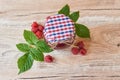 Fresh raspberry jam in a glass jar on a wooden table, next to fresh raspberries with green leaves. homemade jam and preserves for Royalty Free Stock Photo