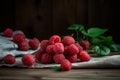 A lot of red Ffresh raspberry and green leaves on old wooden table and gray napkin Royalty Free Stock Photo