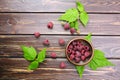 Fresh raspberry red berries with green leaves in bowl on wooden table Royalty Free Stock Photo