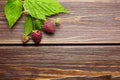 Fresh raspberry, red berries with green leaves on wooden table Royalty Free Stock Photo