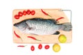 Fresh raw Asian Sea Bass fish on wooden cutting board with lemon, tomato and chilli on white background, top view. Seafood asian