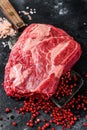 Fresh raw beef marbled steak. Chuck eye roll on a cleaver. Black background. Top view Royalty Free Stock Photo