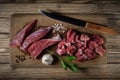 fresh raw beef meat cut into pieces in the process of cooking lies on a wooden cutting board with a kitchen knife, herbs and Royalty Free Stock Photo