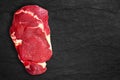 Fresh raw beef steak meat on the black stone plate. Top view, place for text Royalty Free Stock Photo