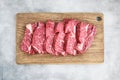 Fresh raw beef steaks on wooden cutting board on gray background. Copy space, top view