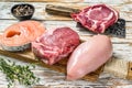 Fresh raw beef striploin steak, chicken breast fillet, pork and salmon steak. White wooden background. Top view Royalty Free Stock Photo