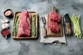 Fresh raw beef tenderloin with seasonings and rosemary, a whole uncut piece, on gray stone background