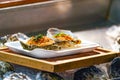 Fresh Raw big couple Oysters on the foam dish and wooden plate topping by fried garlic and leaf the ready to serve