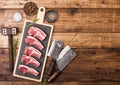 Fresh raw butchers lamb beef cutlets on chopping board with vintage meat hatchets and hammer on wooden background.Salt, pepper and Royalty Free Stock Photo