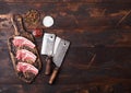 Fresh raw butchers lamb beef cutlets on chopping board with vintage meat hatchets on wooden background.Salt, pepper and oil in Royalty Free Stock Photo