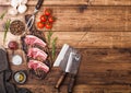 Fresh raw butchers lamb beef cutlets on chopping board with vintage meat hatchets on wooden background.Salt, pepper and oil with Royalty Free Stock Photo