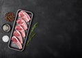 Fresh raw butchers lamb beef cutlets in plastic tray with fresh rosemary on black background.Salt, pepper and oil in steel bowl. Royalty Free Stock Photo