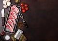 Fresh raw butchers lamb beef cutlets in plastic tray with vintage meat hatchet and fork with knife on brown background.Salt,