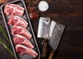 Fresh raw butchers lamb beef cutlets in plastic tray with vintage meat hatchets on wooden background.Salt, pepper and oil in steel Royalty Free Stock Photo