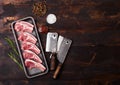 Fresh raw butchers lamb beef cutlets in plastic tray with vintage meat hatchets on wooden background.Salt, pepper and oil in steel Royalty Free Stock Photo