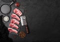Fresh raw butchers lamb beef cutlets on stone board with vintage hatchet on black stone background. Salt and pepper with pan Royalty Free Stock Photo