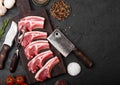 Fresh raw butchers lamb beef cutlets on stone board with vintage meat fork and knife and hatchet on black background.Salt, pepper Royalty Free Stock Photo