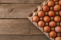 Fresh raw chicken eggs in carton on wooden table, top view. Space for text Royalty Free Stock Photo
