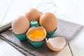 Fresh raw chicken eggs in an cartons egg box. Broken egg, yolk. Organic food for good health high protein on white wooden