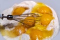 Fresh raw chicken eggs in flour close-up. Mix the broken raw eggs and wheat flour with a whisk to make the dough. The concept of h