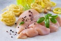 Fresh raw chicken fillet with spices and pasta on gray concrete, stone or slate.