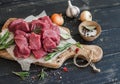 Fresh raw chopped beef on an olive board, spices, herbs and vegetables on dark wooden background. Royalty Free Stock Photo