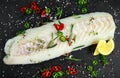 Fresh Raw Cod loin fillet with rosemary, chillies, cracked pepper and lemon on stone board Royalty Free Stock Photo