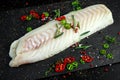 Fresh Raw Cod loin fillet with rosemary, chillies, cracked pepper on stone board Royalty Free Stock Photo