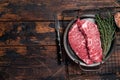 Fresh raw Denver Steak, beef meat with sea salt, seasonings and spices, ready to grill. Wooden background. Top view