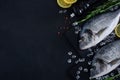 Raw dorada fish on dark background with rosemary, lemon and pepper. Royalty Free Stock Photo