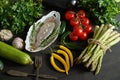 Fresh raw dorada fish in a white dish with a set of vegetables on a black table Royalty Free Stock Photo