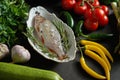 Fresh raw dorada fish in a white dish with a set of vegetables on a black table Royalty Free Stock Photo