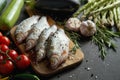 Fresh raw dorada fish on a wooden board with a set of vegetables on a black table Royalty Free Stock Photo