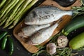 Fresh raw dorada fish on a wooden board with a set of vegetables on a black table Royalty Free Stock Photo