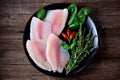 Fresh raw fillet of tilapia fish with thyme, rosemary, basil and chili pepper.