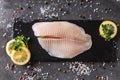 Fresh raw fillet white fish Pangasius with spices and lemon on dark stone background. Royalty Free Stock Photo