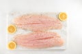 Fillet of sea bass and slices of pink lemon close up on a marble cutting board on white background