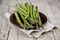Fresh raw garden asparagus closeup on brown ceramic plate and linen napkin on rustic wooden table background. Green spring