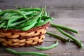 Fresh raw green beans in a brown basket and on a vintage wooden table. Young beans pods photo. Green string beans crop