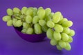 Green grapes in bowl on proton purple background