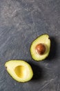 Fresh raw halfs of avocado on a dark stone table, healthy eating concept, top view with copy space