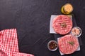 Fresh raw hamburger patties or cutlet on brown board ready to cook on black textured background. Royalty Free Stock Photo