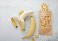 Fresh raw healthy bananas with package of dried banana chips on light board Royalty Free Stock Photo