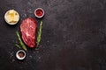 Fresh raw marbled beef rib eye steak, butter and spices on black stone background, copy space Royalty Free Stock Photo