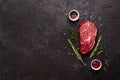 Fresh raw marbled beef rib eye steak, herbs and spices on black stone background, copy space Royalty Free Stock Photo
