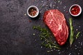 Fresh raw marbled beef rib eye steak and spices on black stone background, copy space Royalty Free Stock Photo