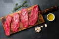 Fresh raw meat beef steaks. Beef tenderloin on wooden board, spices, herbs, oil on slate gray background. Food cooking background Royalty Free Stock Photo