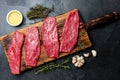 Fresh raw meat beef steaks. Beef tenderloin on wooden board, spices, herbs, oil on slate gray background. Food cooking background Royalty Free Stock Photo