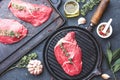 Fresh raw meat. Beef Tenderloin and marbled beef steaks on grill pan and frying board with seasoning, black background top view Royalty Free Stock Photo