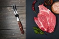 Fresh raw meat steak, spices and a fork on a black stone, top view. Space for text Royalty Free Stock Photo